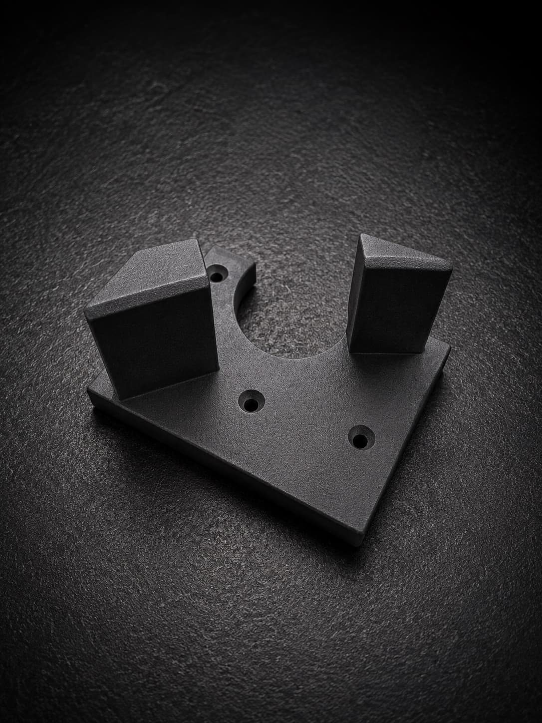 An SLS-printed nylon cradle fixture with two angled jaws around a half-round cutout